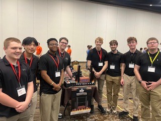 Nine members of the Roller Coaster Creation Club standing with their model coaster at a competition.